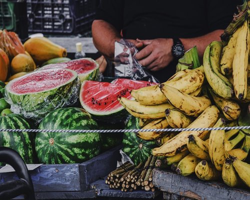 A bunch of yellow bananas next to sliced watermelon on a table